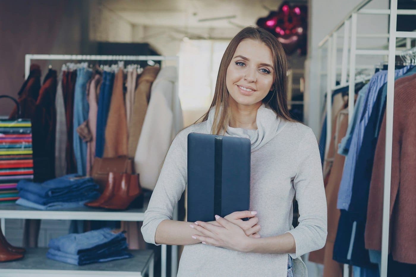Dona de loja de roupas com um tablet entre as araras