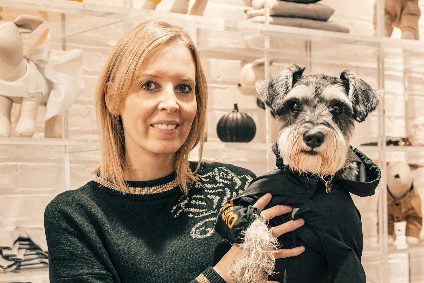 Dona de pet shop com um schnauzer de capa no colo