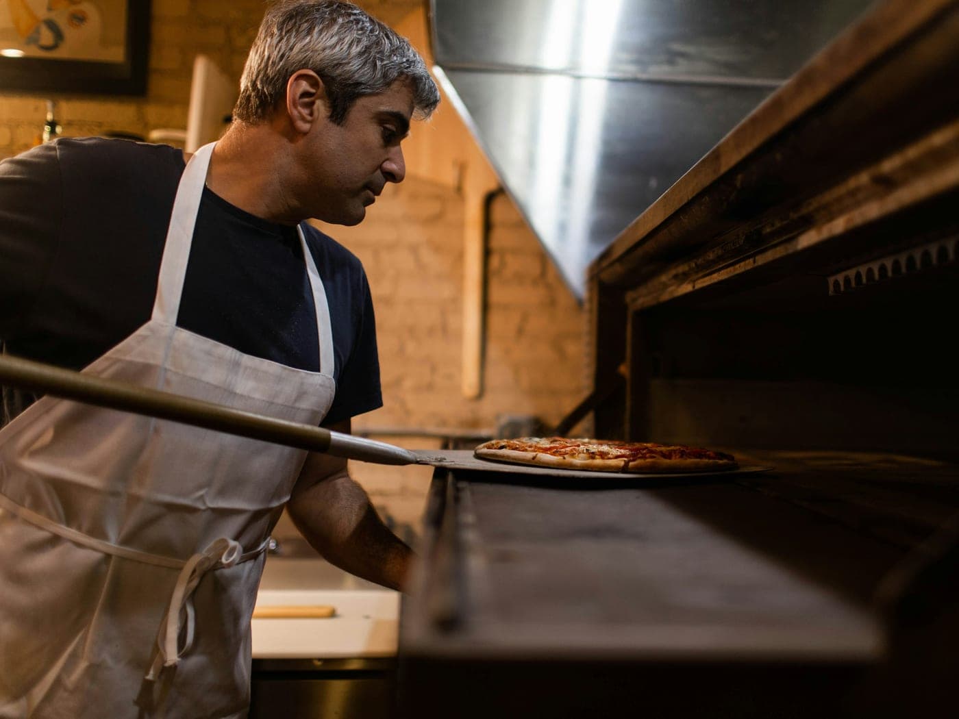 Pizzaiolo colocando uma pizza no forno